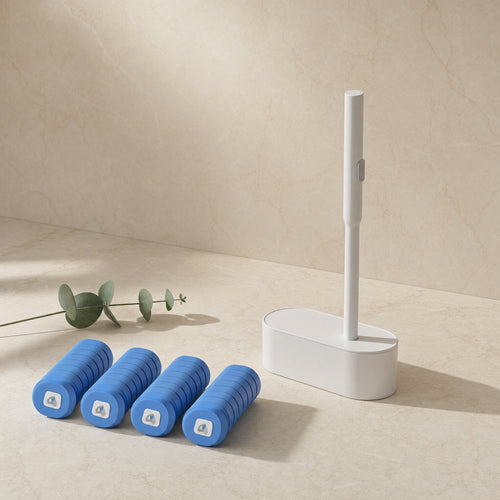 Disposable toilet brush standing in its slim white caddy on a cream studio background