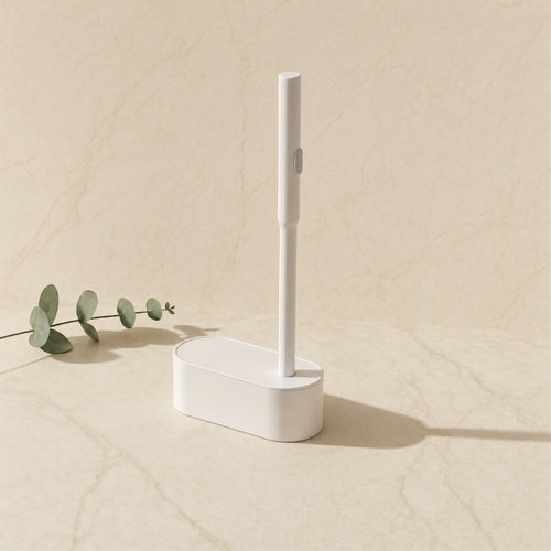 White disposable toilet brush and caddy on a cream marble tile — Wombat Haul