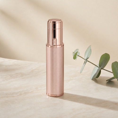 Rose-gold facial hair trimmer standing upright on a cream studio background